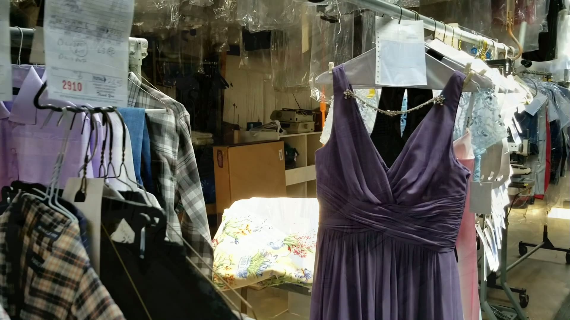 A formal gown hanging with finished orders at Clean Right Cleaners